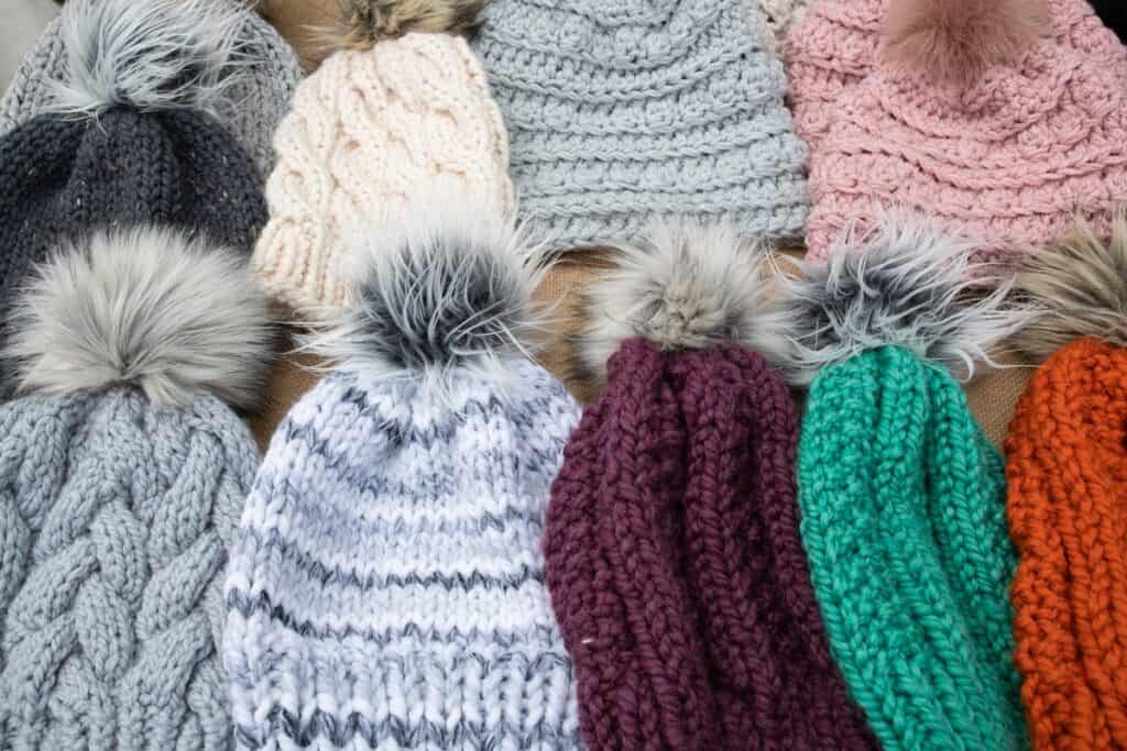Knitted and crocheted hats being sold at a craft fair.