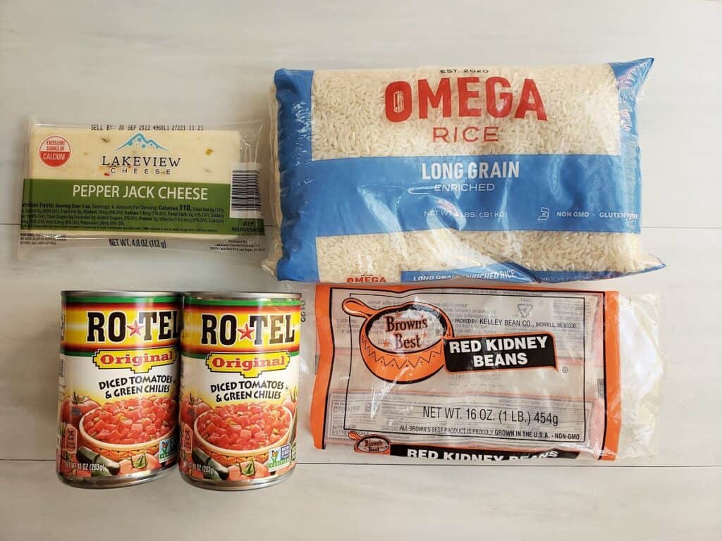 Two cans of rotel tomatoes, a bag of rice, a bag of beans, and a block of cheese.