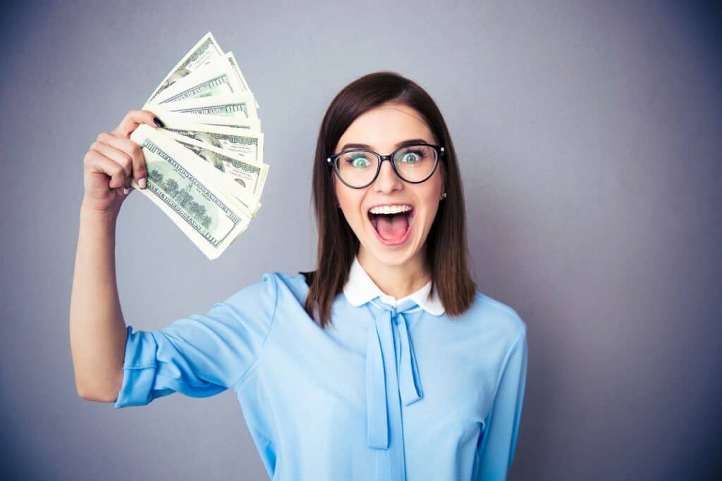 Woman with a silly face holding a bunch of money in her hand.